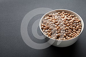 Dry chickpeas in white bowl isolated on dark