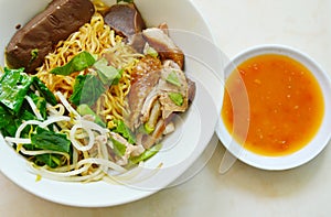 dry Chinese egg noodle topping duck meat and bean sprout on bowl with chili sauce