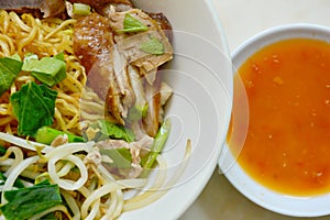 Dry Chinese egg noodle topping duck meat and bean sprout on bowl with chili sauce