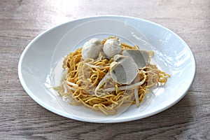 dry Chinese yellow noodles with bean sprout topping pork meatball and slice fish line on plate