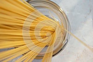 Dry classic spaghetti in glass jar. Ingredient for Italian pasta, top view. Raw food with selective focu