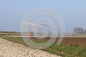 Dry clay fields are sprayed by farmers with water on the island of Goeree Overflakkee in the Netherlands