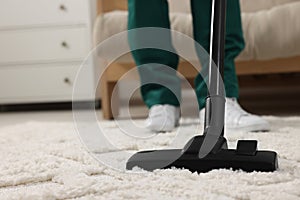 Dry cleaner\'s employee hoovering carpet with vacuum cleaner indoors, closeup. Space for text