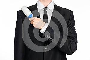 Dry cleaning and business theme: a man in a black suit holding a blue sticky brush for cleaning clothes and furniture from dust is