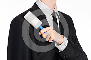 Dry cleaning and business theme: a man in a black suit holding a blue sticky brush for cleaning clothes and furniture from dust is