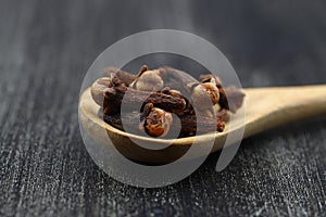 Dry cloves in wooden scoop isolated on white background with clipping path. Top view. Flat lay. selective focus