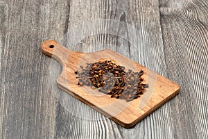 Dry cloves in wooden scoop isolated on wooden background with clipping path. Top view. Flat lay. selective focus