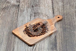 Dry cloves in wooden scoop isolated on wooden background with clipping path. Top view. Flat lay. selective focus