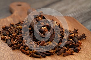 Dry cloves in wooden scoop isolated on wooden background with clipping path. Top view. Flat lay. selective focus