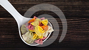 Dry colorful Italian pasta farfalle or bows in spoon