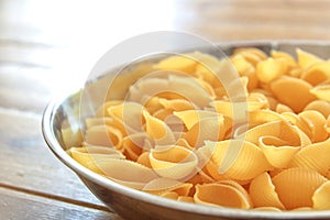 Dry conchiglie pasta shells in a stainless steel bowl