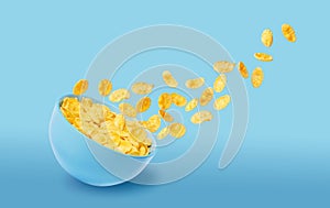 Dry corn flakes in a blue ceramic plate, some of the corn flakes are flying in the air. traditional cornflakes breakfast concept
