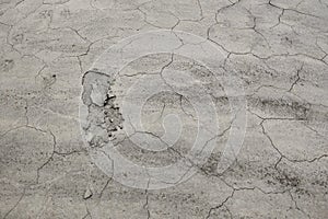 Dry cracked clay surface of the earth. The texture of the dry clay with cracks. Human footprints in the dry soil with faults