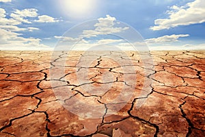 Dry cracked soil in drought land under blue sky.