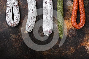 Dry cured chorizo and fuet salami sausages hanging on dark background with copy space