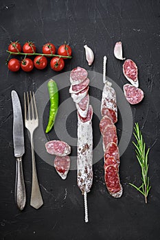 Dry cured fuet salami sausage slices  on balck background, top view