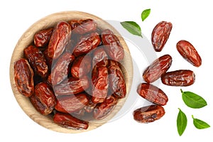 Dry dates with green leaves in wooden bowl isolated on white background. Top view. Flat lay pattern