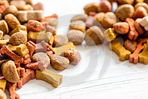 Dry dog food in bulk on wooden background close up