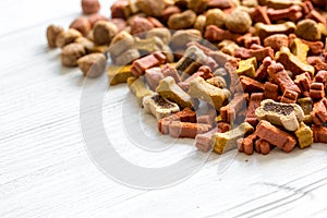 Dry dog food in bulk on wooden background close up