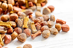 Dry dog food in bulk on wooden background close up