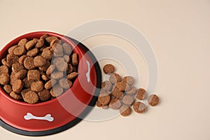 Dry dog food and feeding bowl on beige background. Space for text