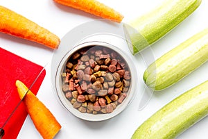 Dry dogfood with carrot and zucchini on table background top view
