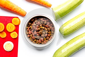 Dry dogfood with sliced vegetables on table background top view