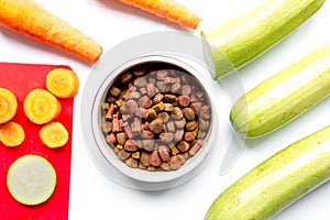 Dry dogfood with sliced vegetables on table background top view