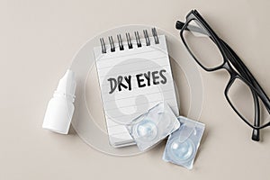 Dry eyes concept with contact lens, eye drop bottle and eyeglasses on beige background