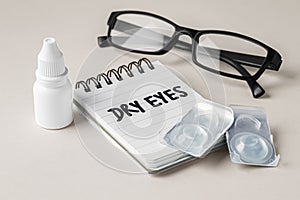 Dry eyes concept with contact lens, eye drops and eyeglasses on beige background