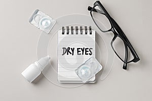 Dry eyes concept with contact lenses, eye drops and eyeglasses on beige background