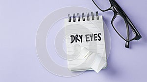 Dry eyes concept with eye drops with eyeglasses on pastel violet background, top view