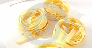 dry fettuccine pasta. traditional italian food close up. uncooked pasta on a white background. egg noodles.