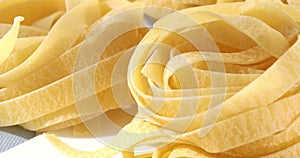 dry fettuccine pasta. traditional italian food close up. uncooked pasta on a white background. egg noodles.