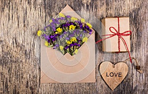 Dry field flowers in a paper envelope. Romantic letter. A wooden heart.