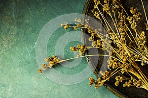 Dry flowers on vintage old metal dish. Dark stone concrete background. Copy space for text. Cozy fall atmosphere