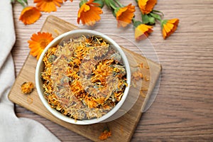 Dry and fresh calendula flowers on wooden table, flat lay. Space for text