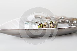 Dry fruit Indian sweets wrapped in silver foil kep in a plate on white background