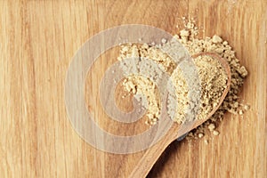 Dry ginger in a wooden spoon on a textured