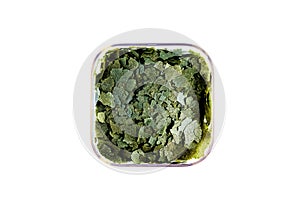 Dry green compound fish feed flakes in a transparent box on White background. Top view