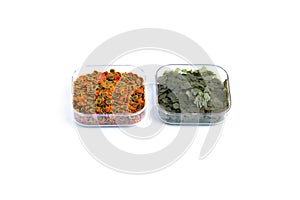 Dry green and red compound fish feed flakes in a transparent boxs on White background. Side view