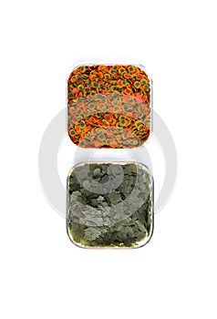 Dry green and red compound fish feed flakes in a transparent boxs on White background. Top view.