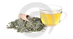 Dry green tea leaves and cup of aromatic beverage on white background