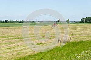 Dry haystack roll and blur tractor ted hay field
