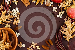 Dry hydrangea flowers, autumn leaves, cinnamon, herbs on brown background. Top view. Decor element with copy space for holiday