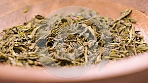 Dry japanese sencha green tea leaves in wooden rustic bowl
