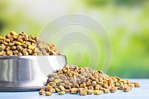 Dry kibble pet food in bowl. Dog or cat food on garden table