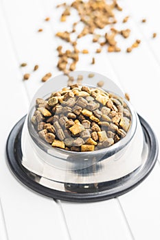 Dry kibble pet food. Dog or cat food in bowl on white table