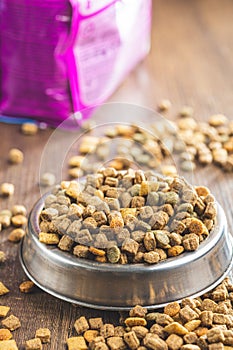 Dry kibble pet food. Dog or cat food in bowl on wooden table