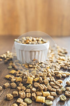 Dry kibble pet food. Dog or cat food in bowl on wooden table